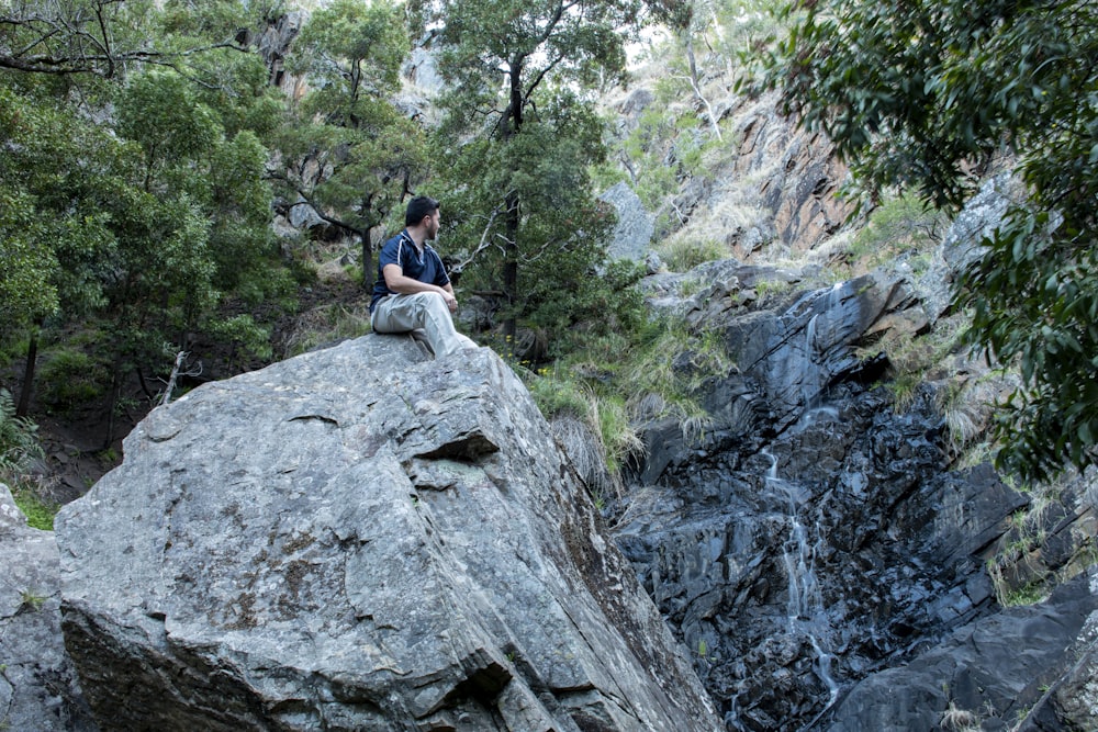 Mujer con camisa azul sentada en la roca durante el día