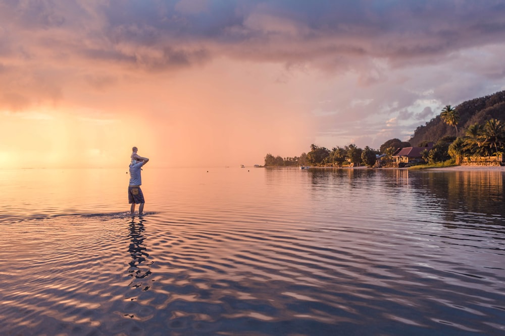 man in white shirt and black pants walking on beach during sunset