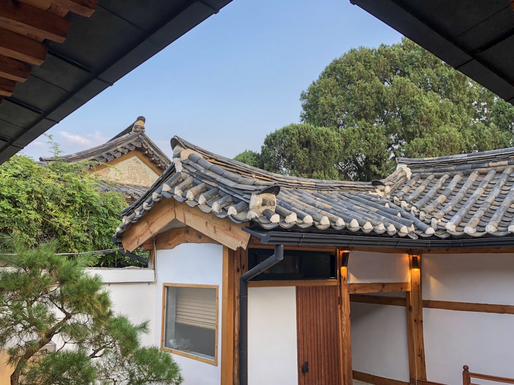 昼間の青空の下、緑の木々の近くの白と茶色の家