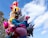 A vibrant cluster of colorful balloons featuring various cartoon characters, including animals and fantastical creatures, set against a backdrop of a clear blue sky with some clouds. The balloons are arranged in a towering display rising above the urban street scene.