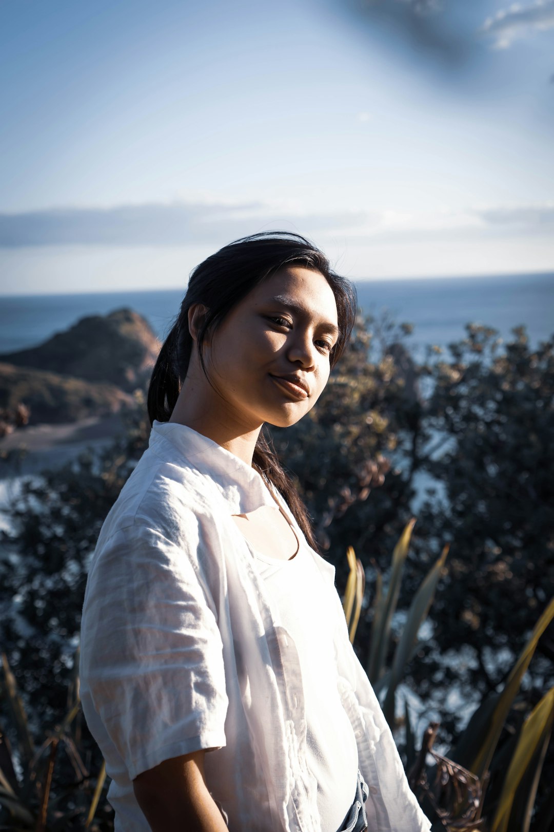 woman in white dress shirt standing near green plants during daytime