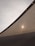 A close-up view of a fabric canopy, with sunlight creating a bright spot on the textured surface. The canopy is stretched taut, with visible seams or supports. The sky in the background is overcast, adding a muted tone to the overall scene.