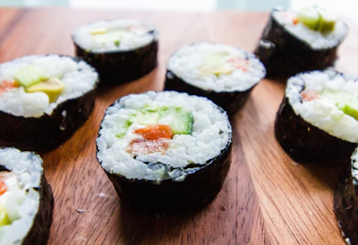 Close-up of colorful sushi rolls artfully arranged on a wooden platter.