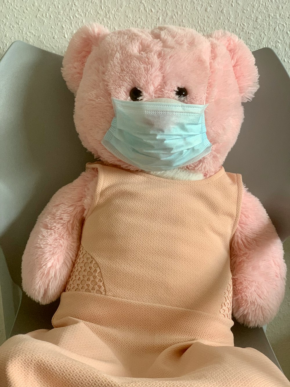 pink bear plush toy on white textile