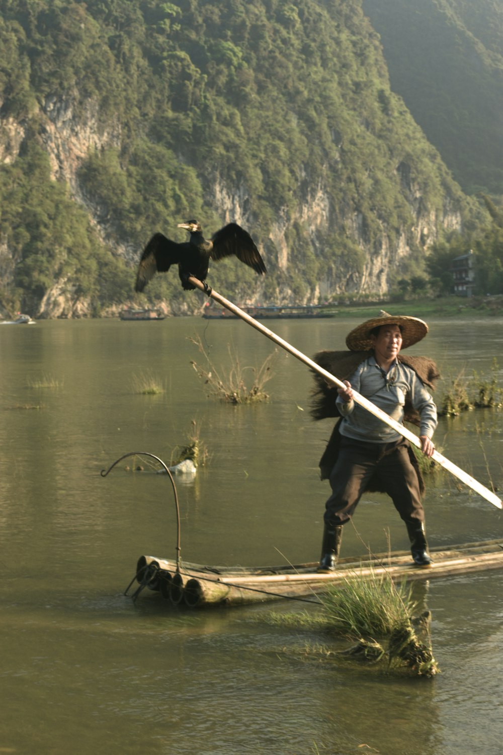 man in blue shirt and black pants holding white fishing rod standing on brown wooden boat