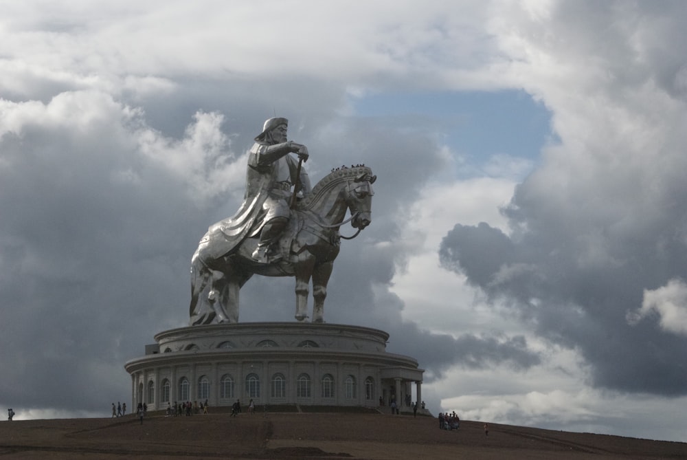 Mann reitet Pferdestatue tagsüber unter bewölktem Himmel