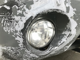 Close-up of a car headlight before renovation, showing yellowed and cloudy plastic.