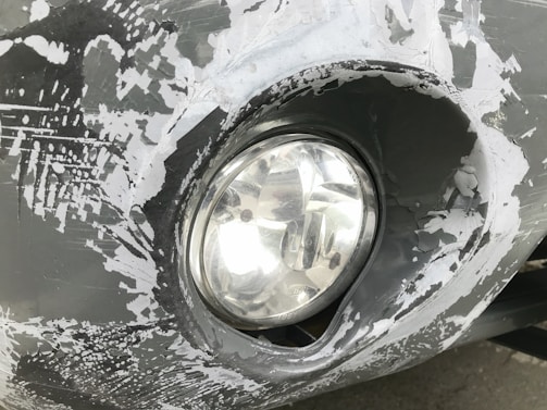 Close-up of a car headlight before renovation, showing yellowed and cloudy plastic.