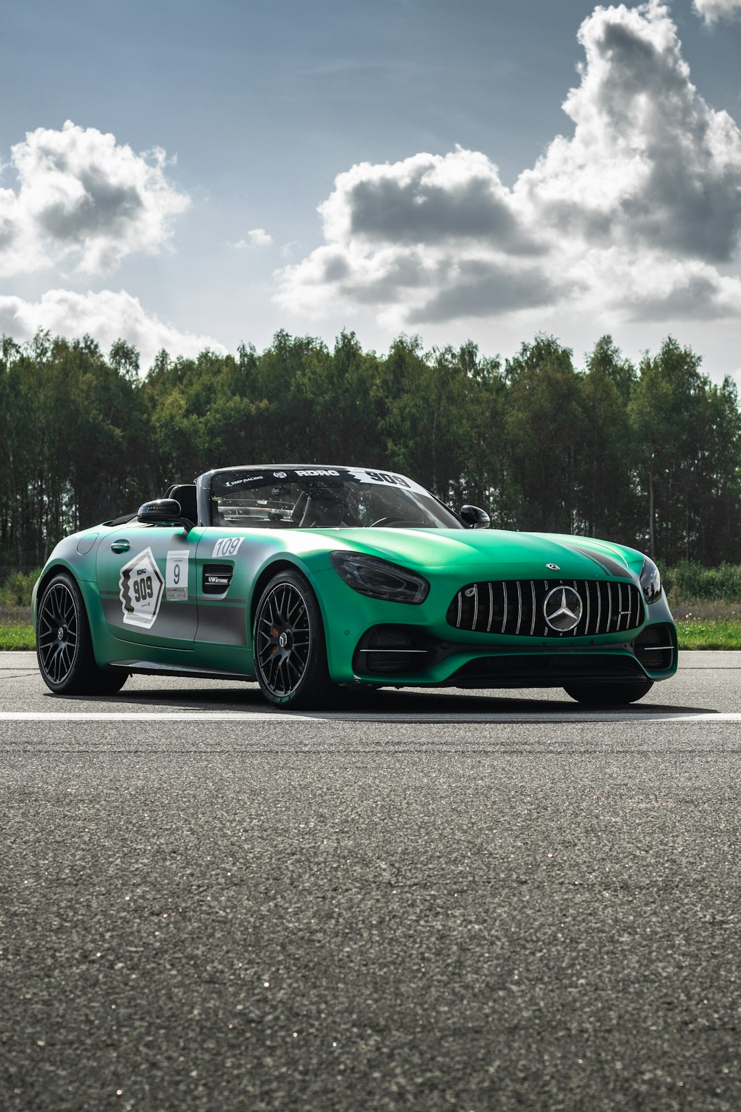 green mercedes benz coupe on gray asphalt road under gray cloudy sky during daytime