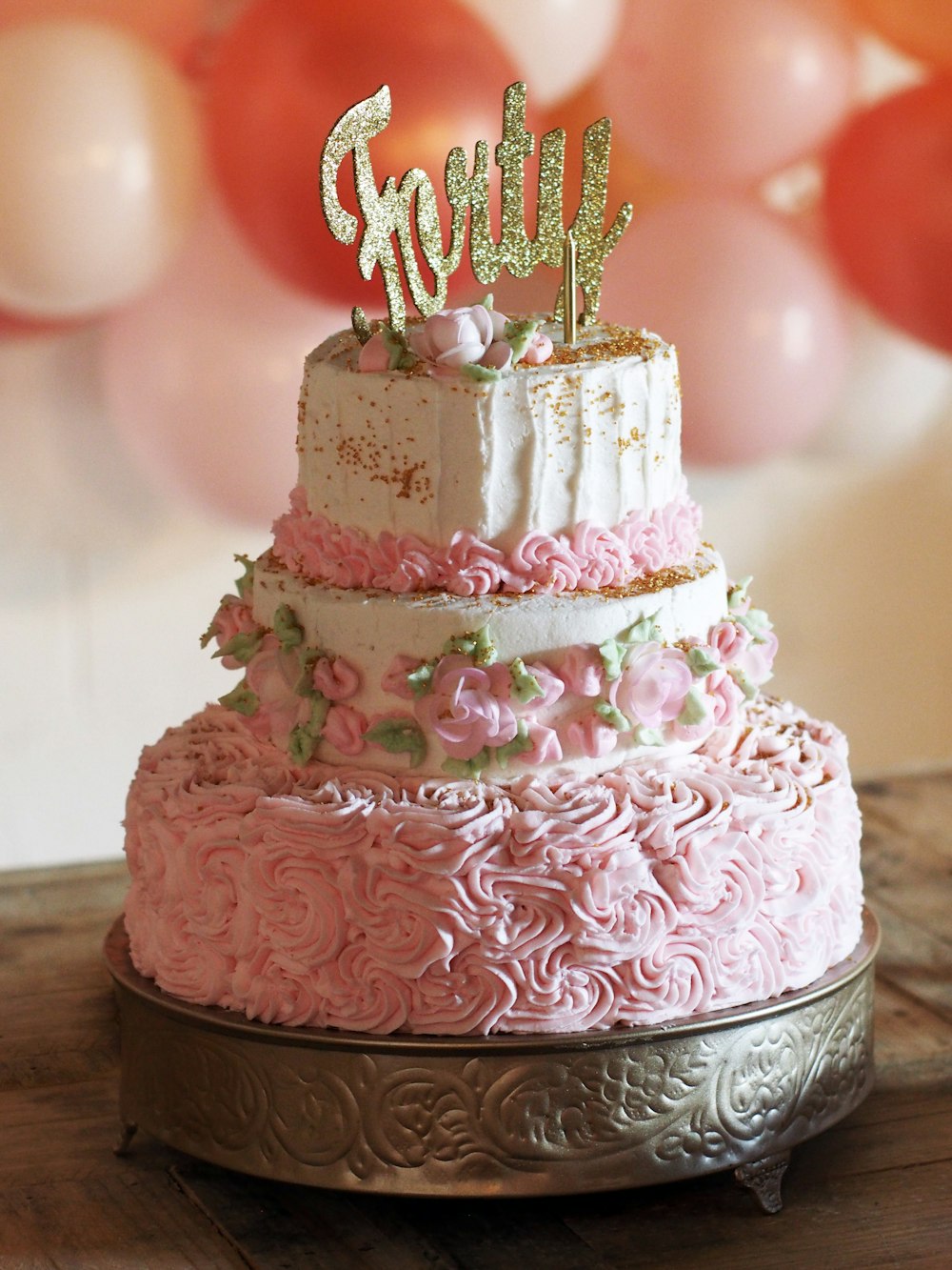 pink and white cake with candles on brown wooden table