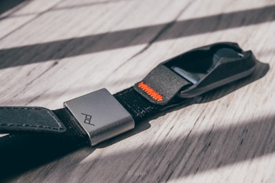 Close-up of a glue gun applying orange elastomer adhesive on a wooden surface.