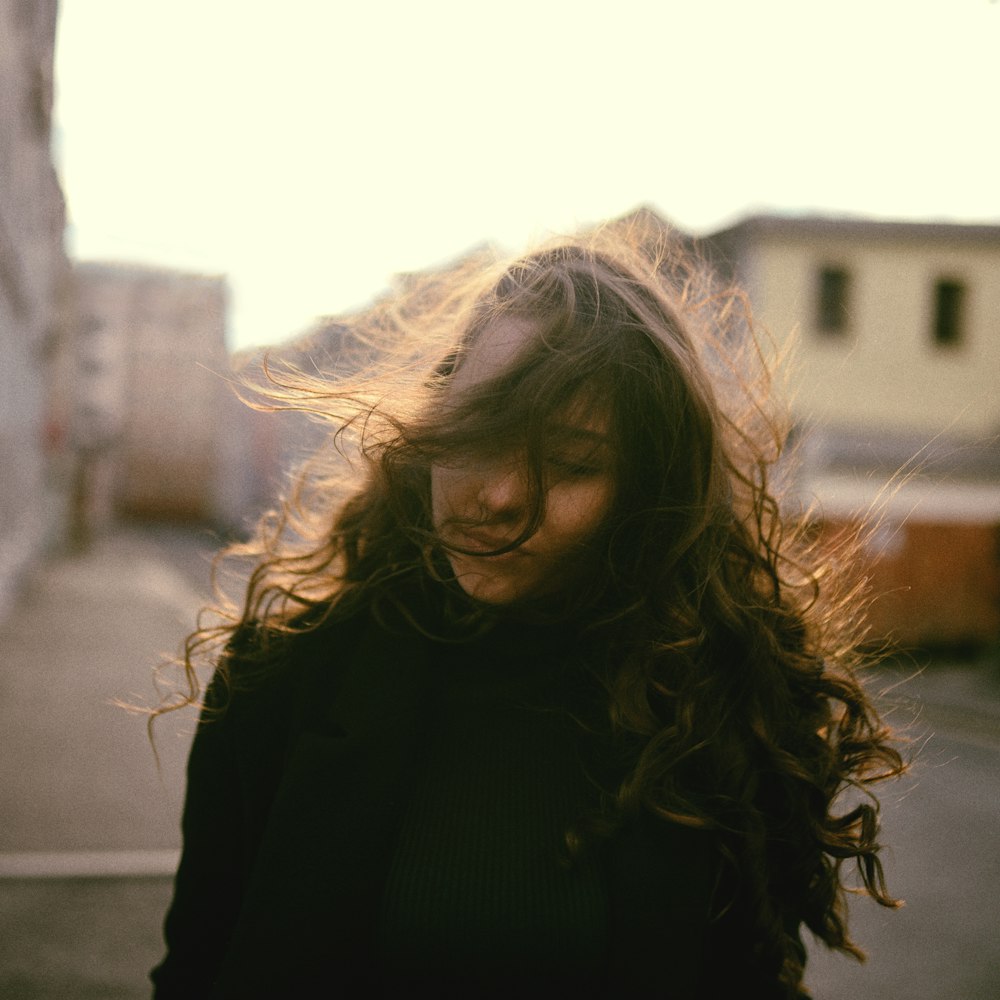 woman in black jacket standing near building during daytime