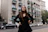 A stylish woman wearing a vibrant, flowing dress standing confidently on a city street.