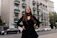 A stylish woman wearing a vibrant, flowing dress standing confidently on a city street.