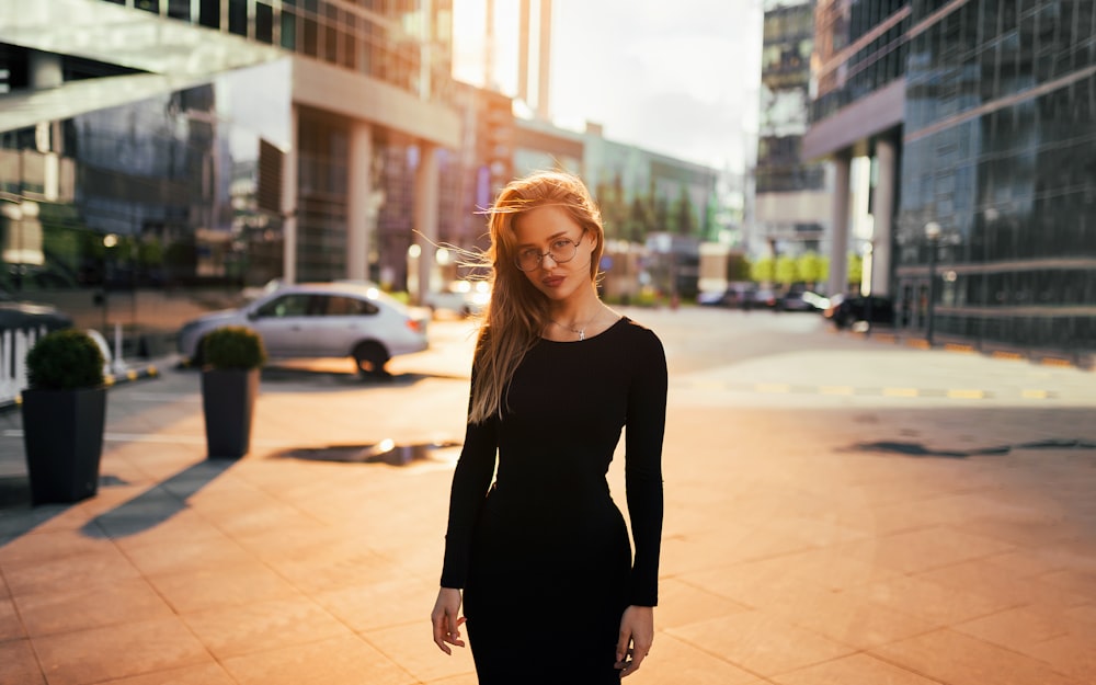 woman in black long sleeve shirt standing on sidewalk during daytime