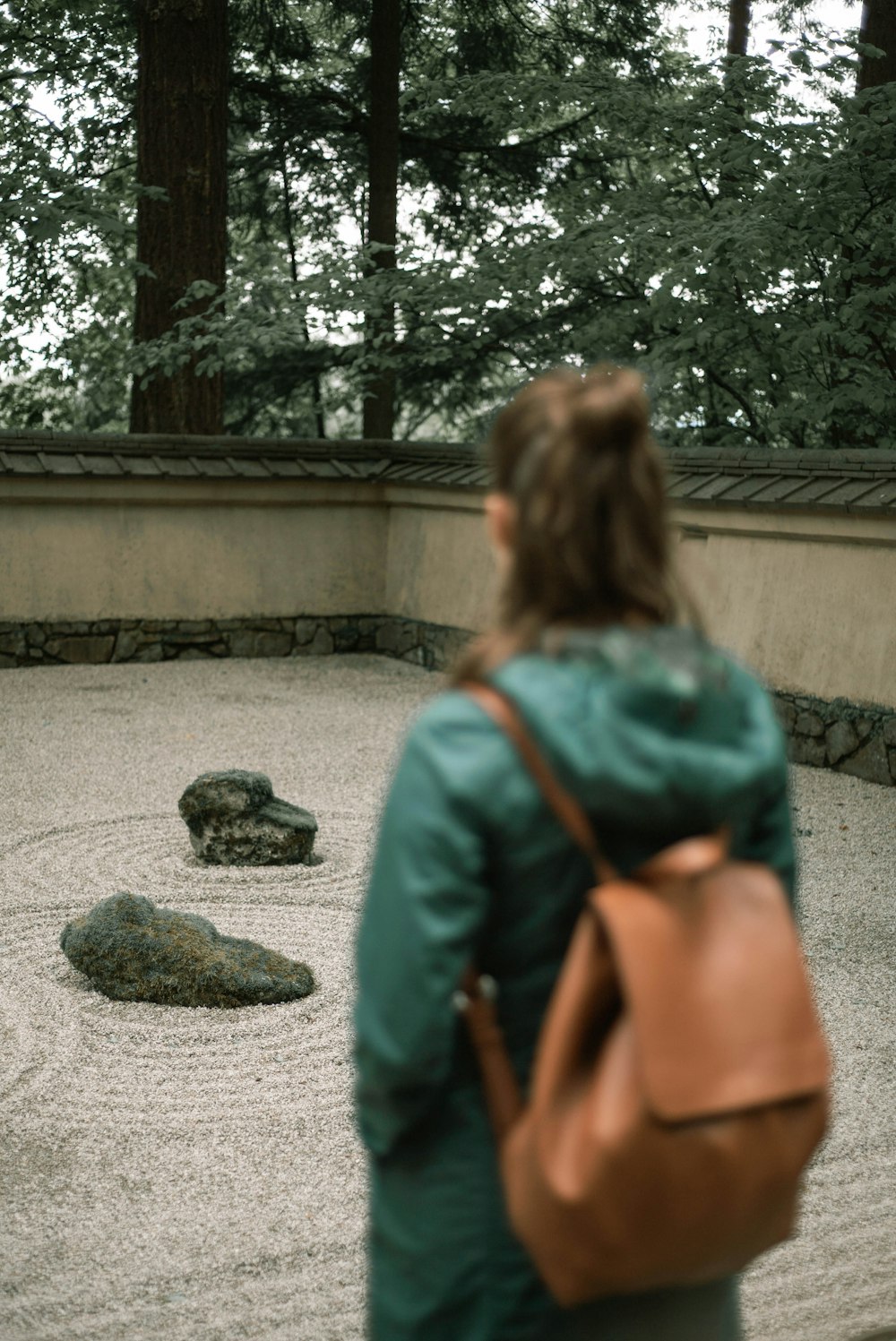 woman in green shirt and orange backpack standing on gray concrete floor during daytime