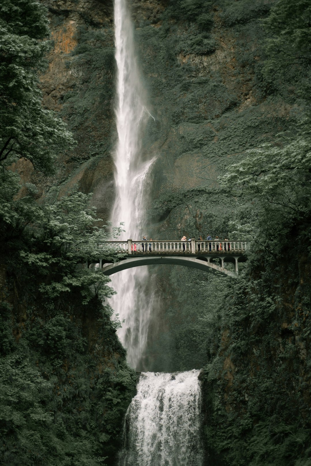 green bridge over waterfalls during daytime