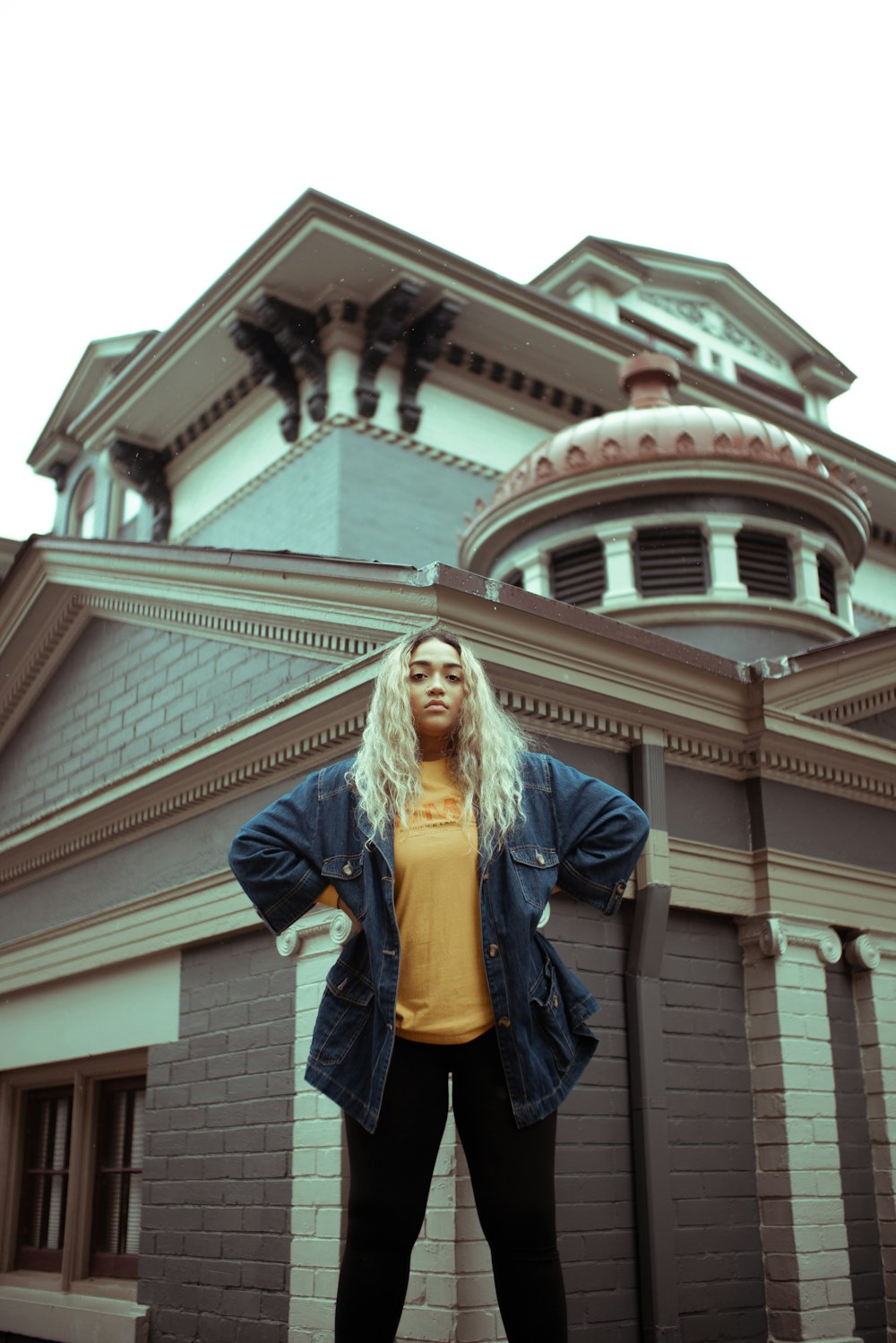 woman in blue jacket standing near brown concrete building during daytime