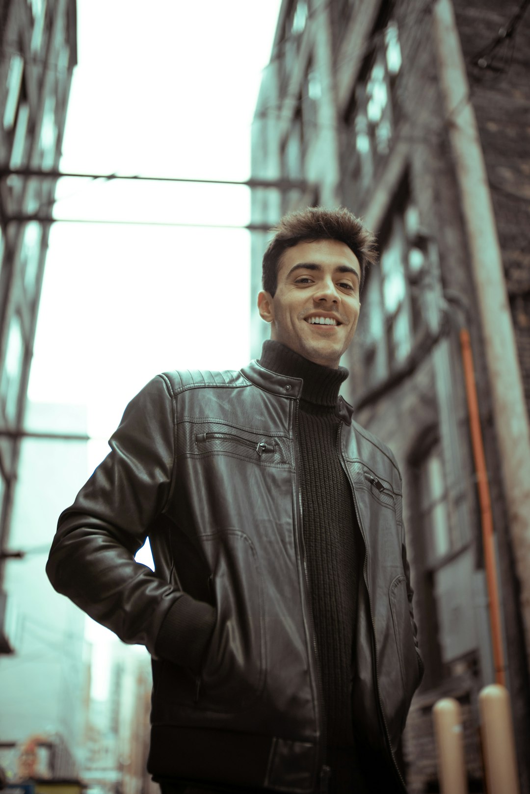 man in black leather jacket standing near window