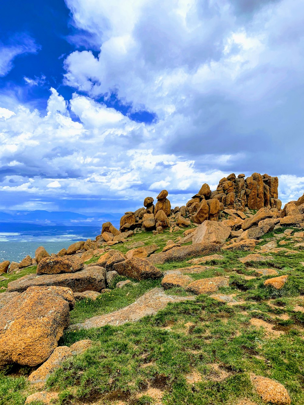 brown rocks on green grass field under blue sky during daytime