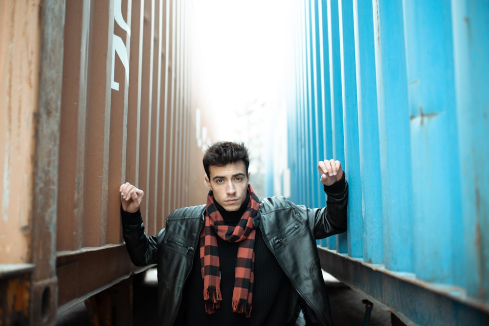 man in black leather jacket standing near blue curtain