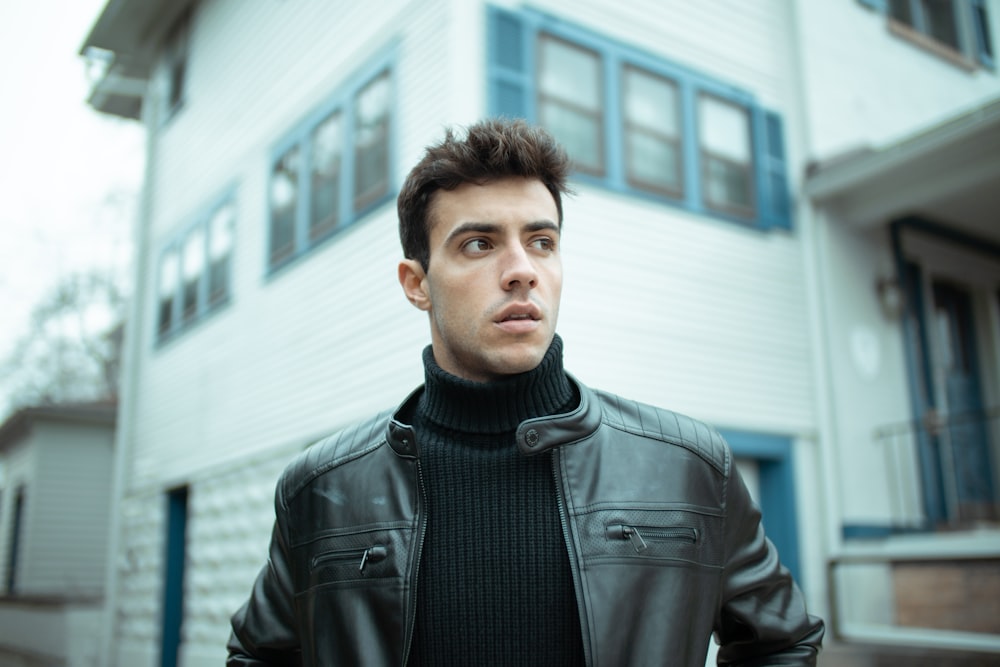 man in black leather jacket standing near building during daytime