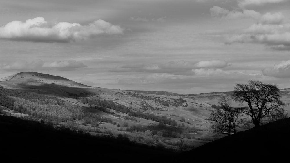 grayscale photo of mountains under cloudy sky