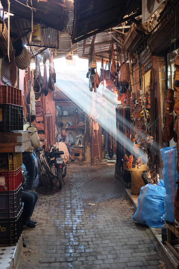 Shafts of sunlight cutting through the slatted roof of a covered souk alley in Marrakech
