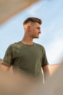 Model wearing a blue t-shirt standing outdoors with natural sunlight
