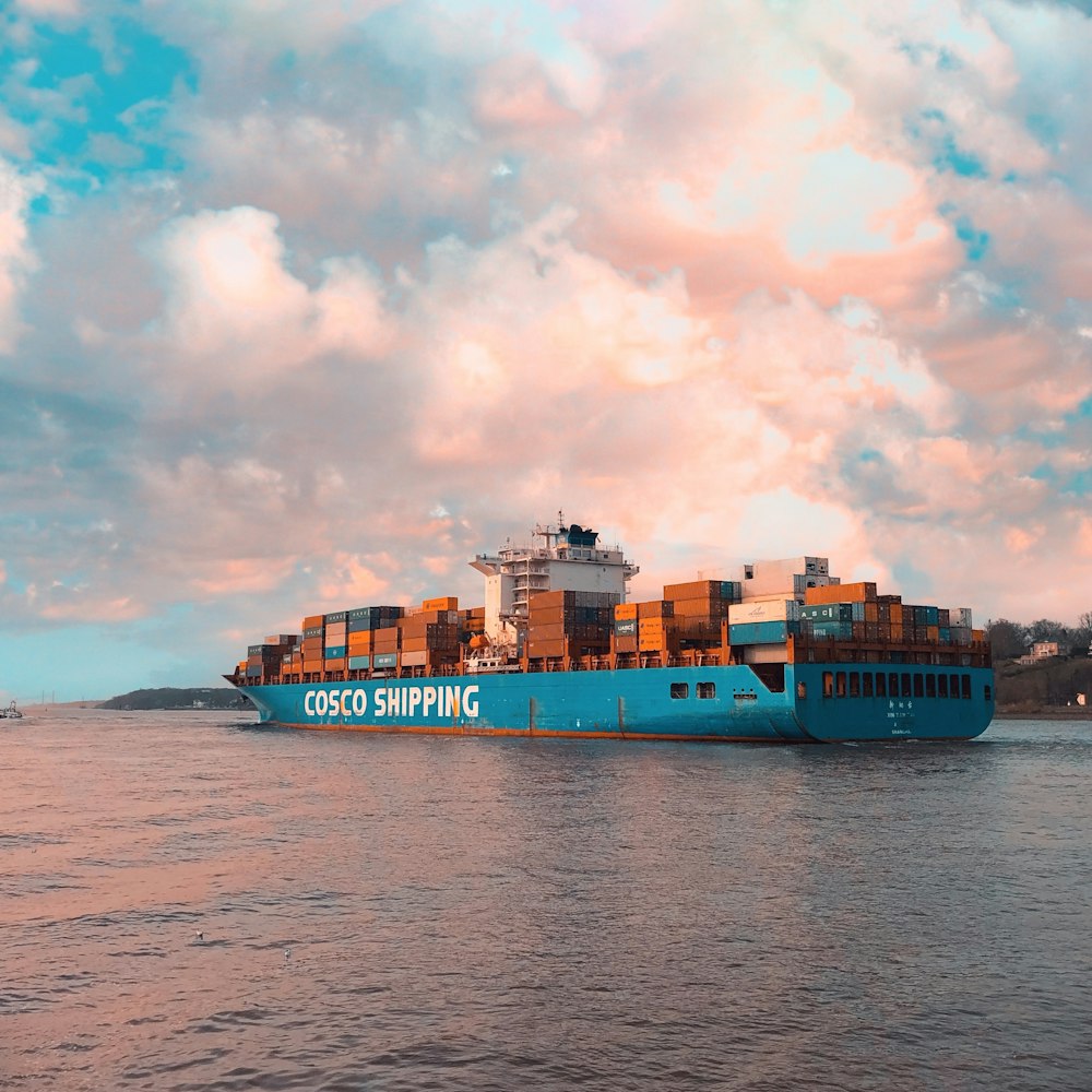 blue cargo ship on sea under cloudy sky during daytime