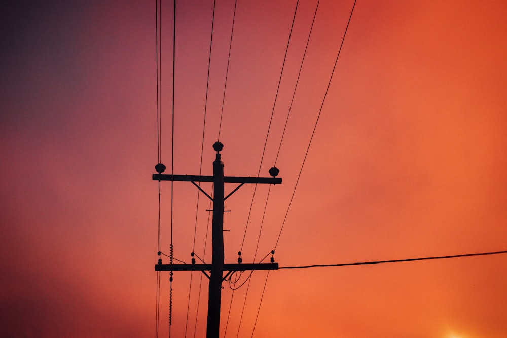 black electric post under orange sky