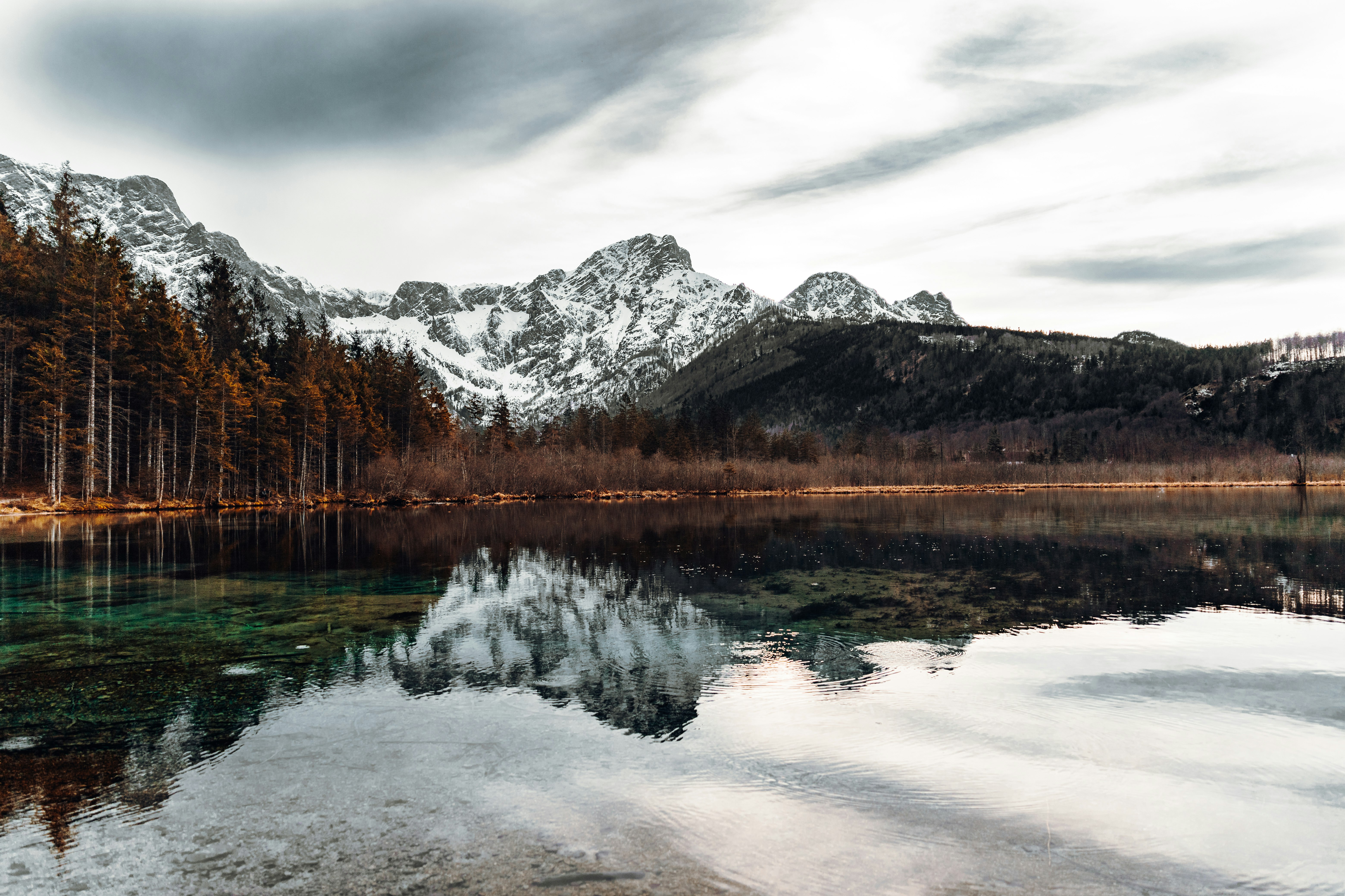 lake near snow covered mountain under cloudy sky during daytime