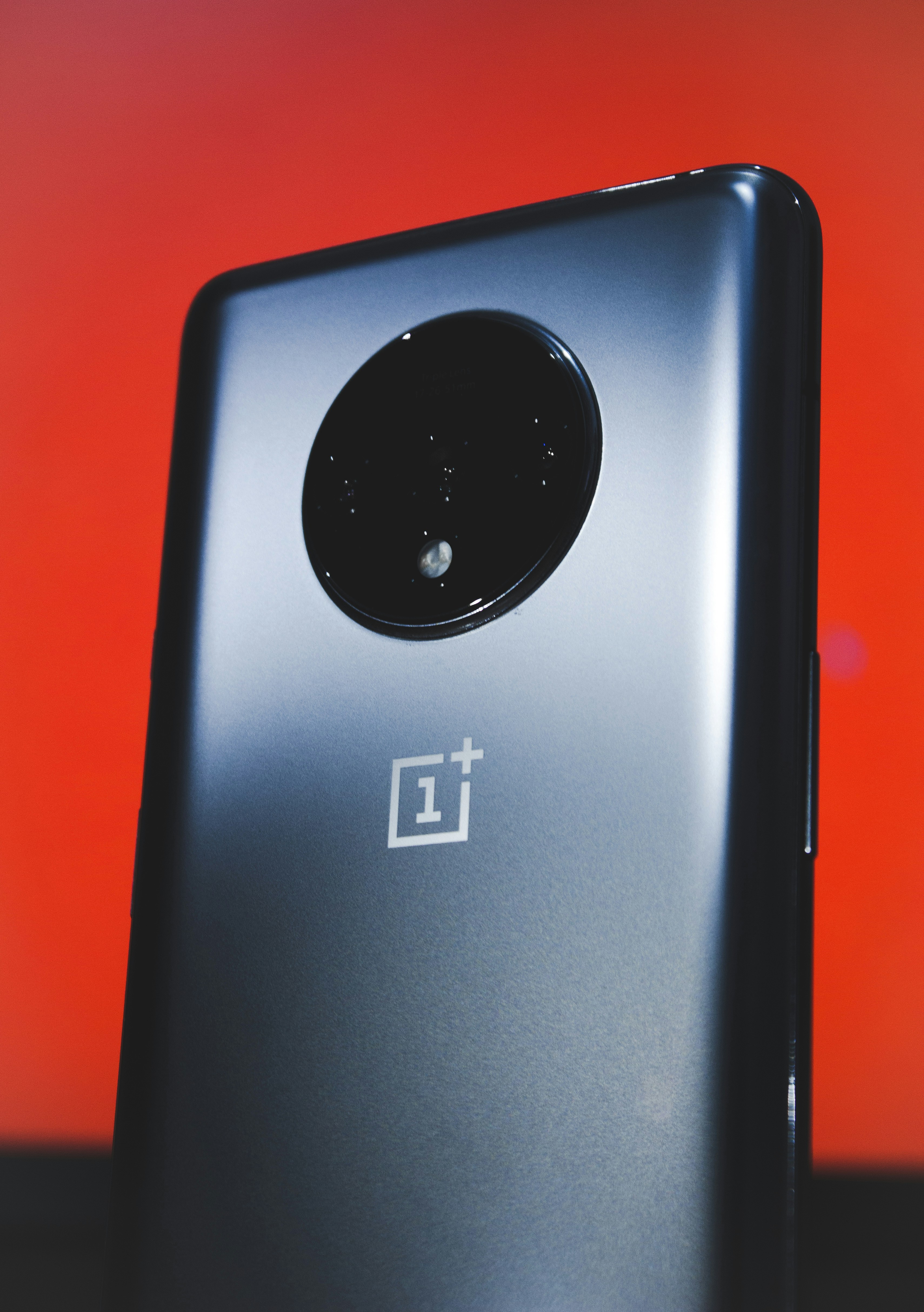 Modern smartphone held against vibrant red Vodafone brand background with dramatic studio lighting