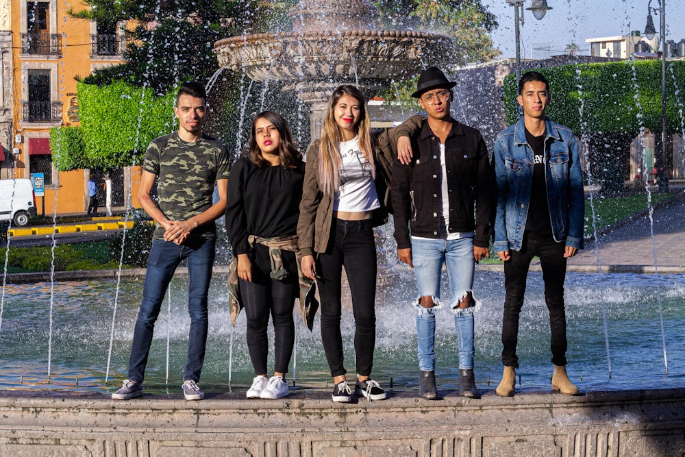 3 women standing beside fountain during daytime