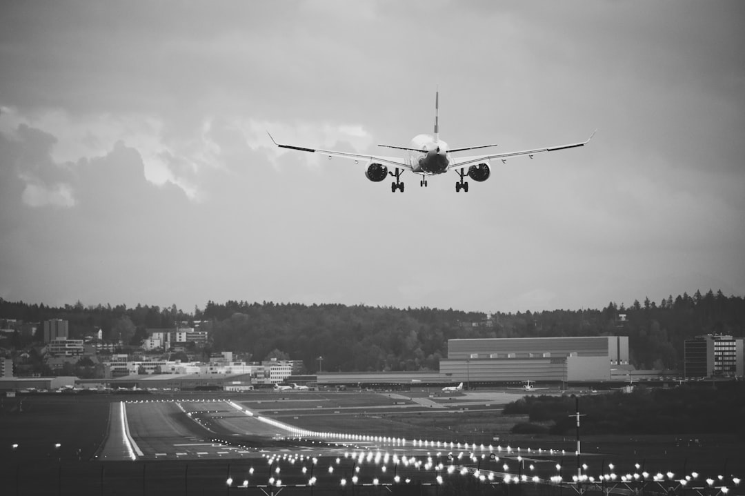 grayscale photo of airplane in the sky, Landing aircraft at the airport in Zurich.