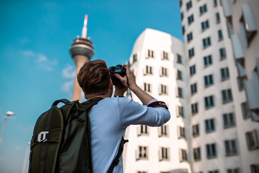 man in white long sleeve shirt using black dslr camera during daytime