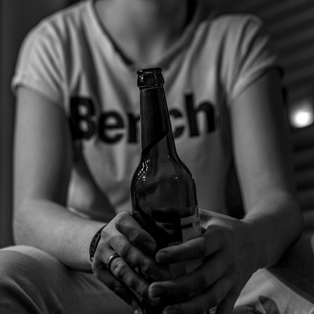 grayscale photo of man holding bottle