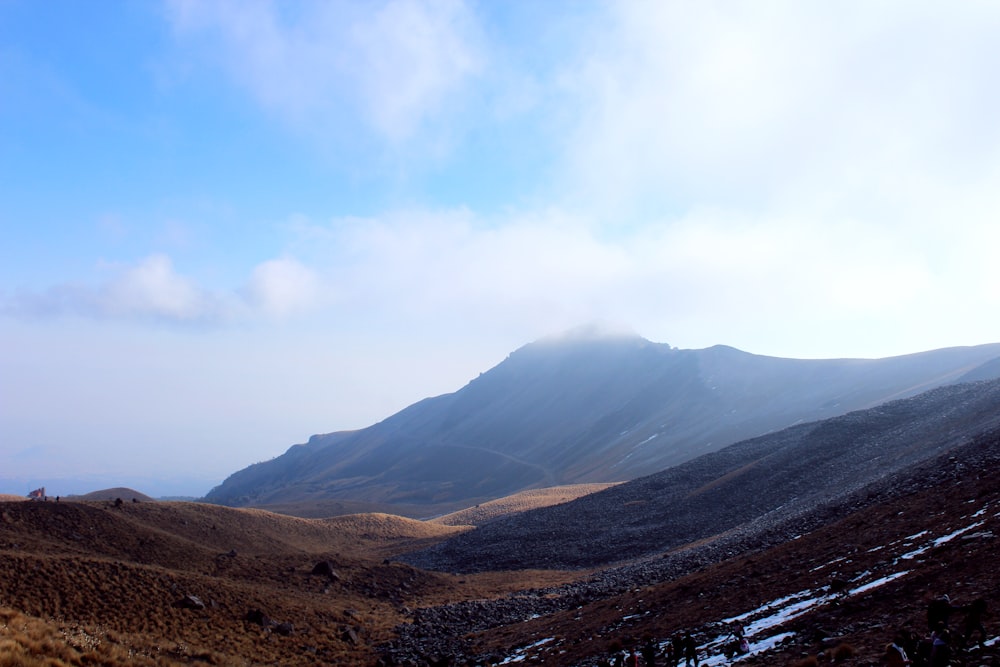 brown and green mountains under white clouds during daytime