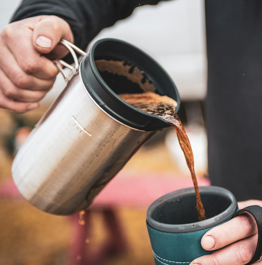 person pouring water on silver steel cup