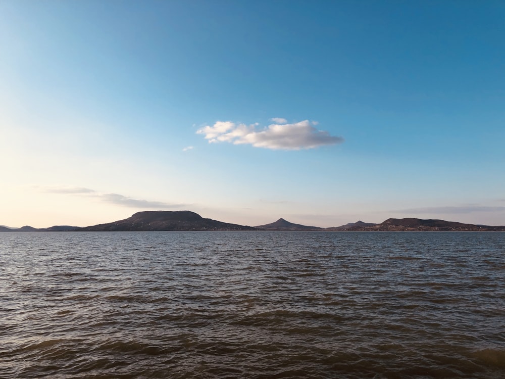 body of water near mountain under blue sky during daytime