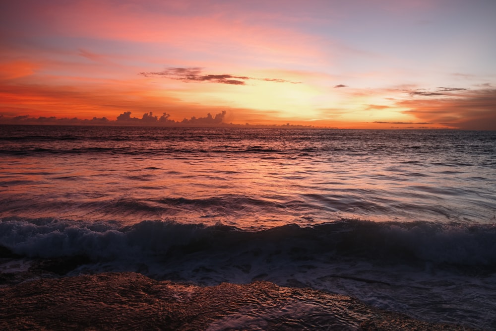 sea waves crashing on shore during sunset