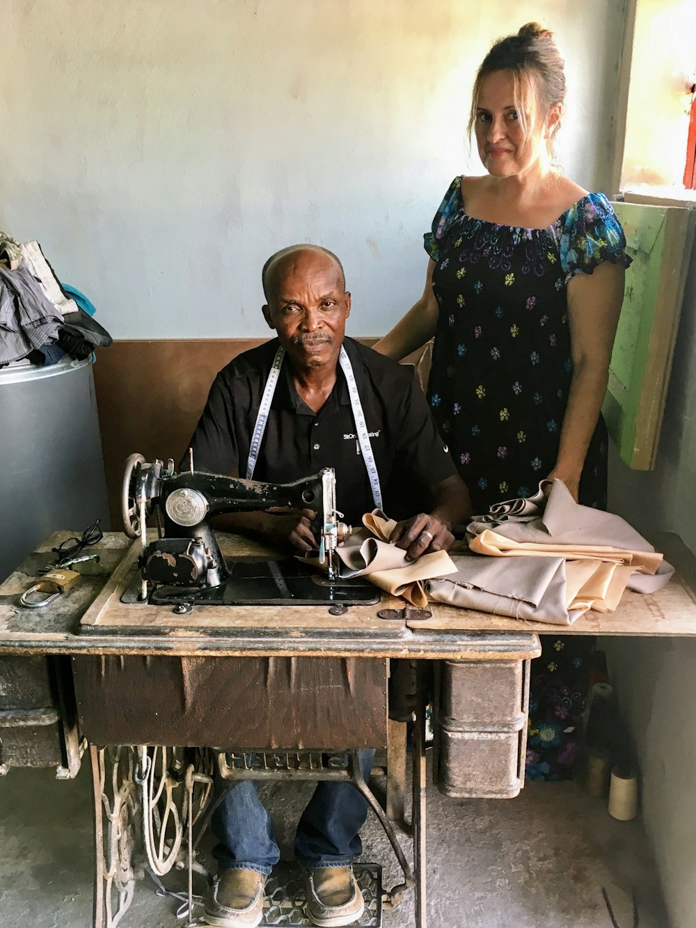 hombre y mujer de pie junto a la máquina de coser