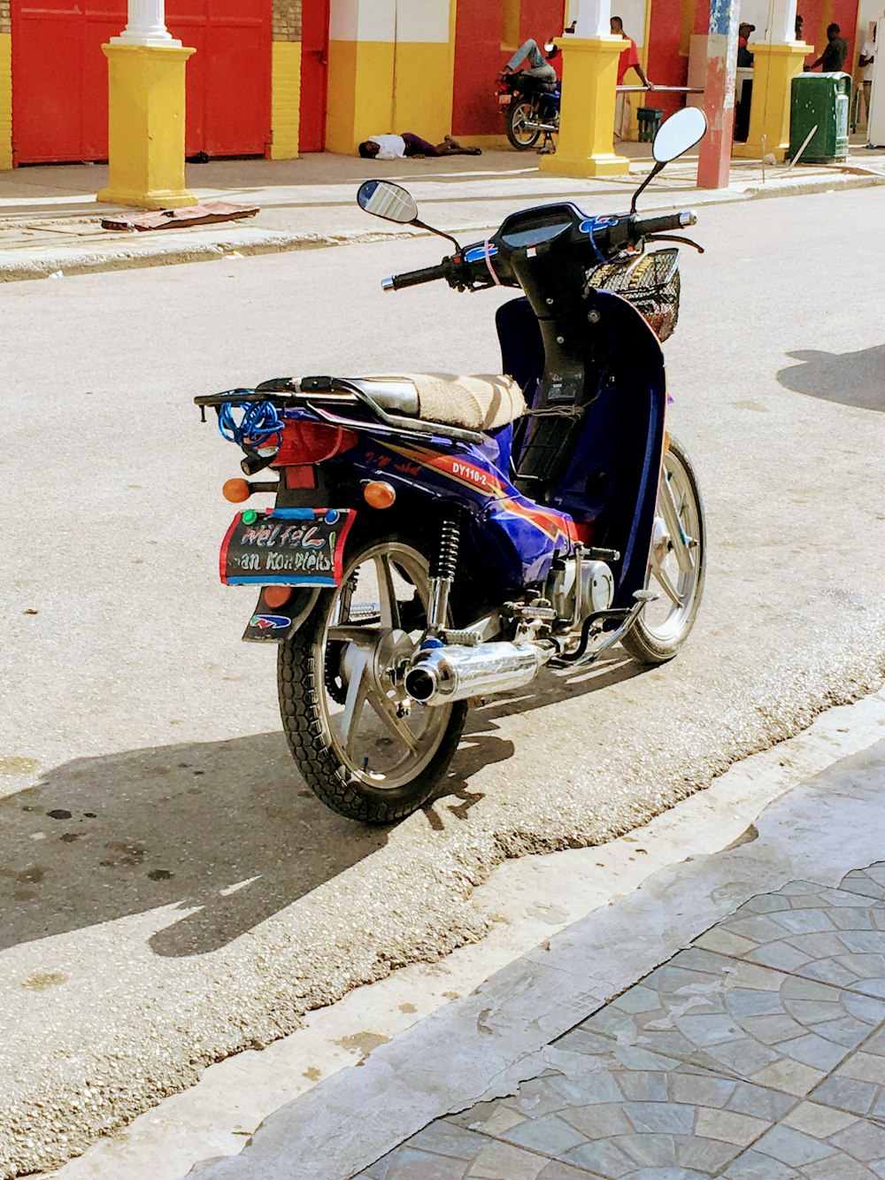 Moto noire et rouge garée sur une route en béton gris pendant la journée