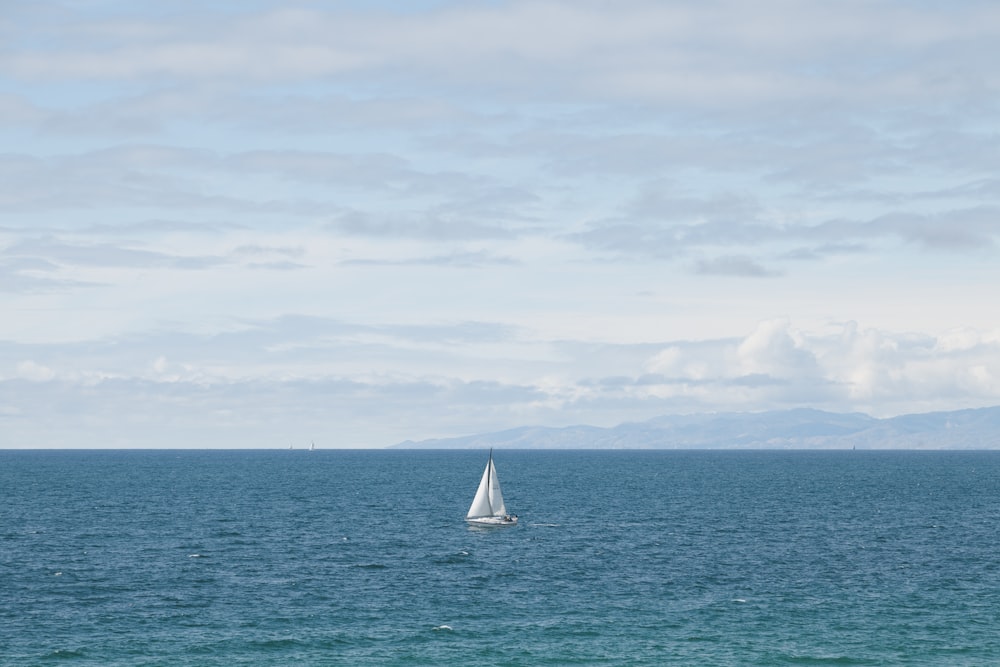 white sailboat on sea under white clouds during daytime