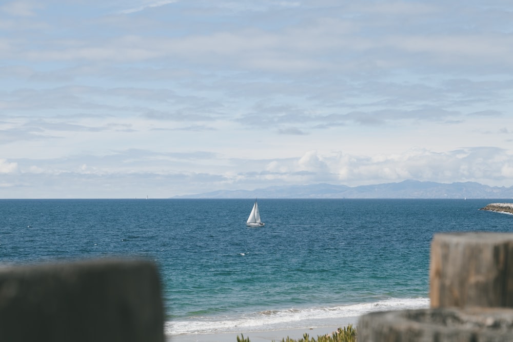 white sailboat on sea under white clouds during daytime