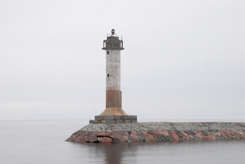 white and red lighthouse near sea during daytime