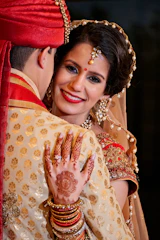A radiant bride adorned in traditional Indian bridal makeup and a floral hairstyle, glowing with confidence and joy.