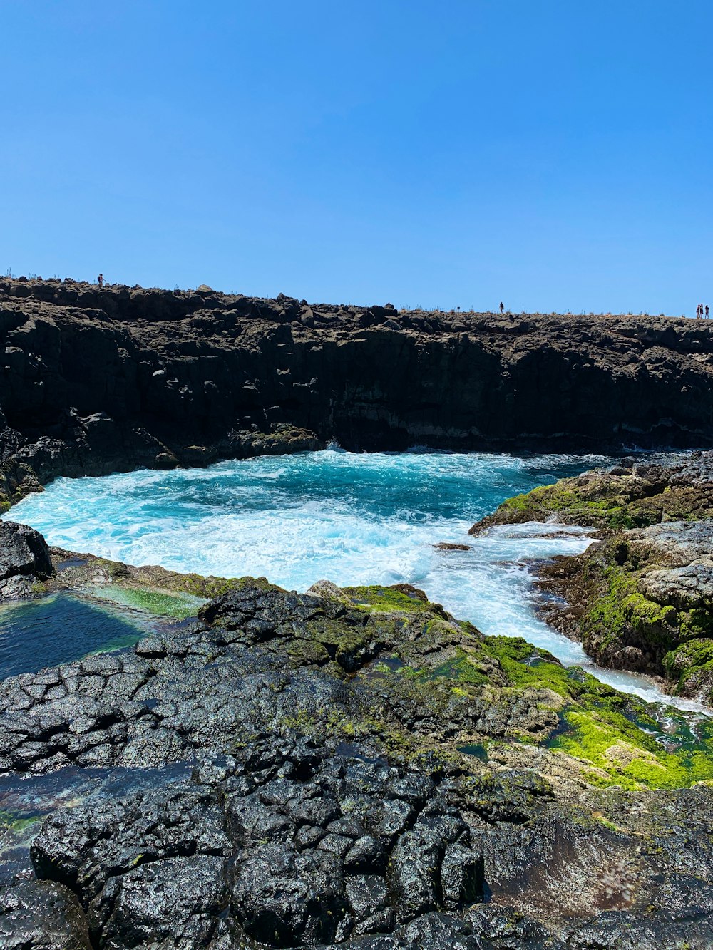 brown rocky mountain beside blue sea under blue sky during daytime