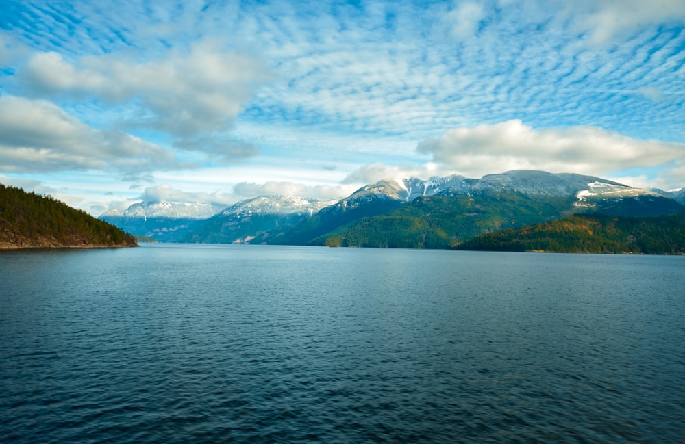 body of water near mountain under blue sky during daytime