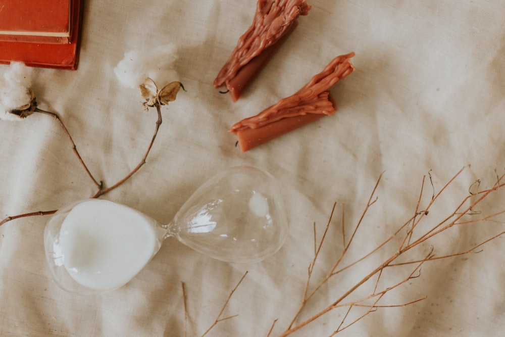 white ceramic bowl beside red dried leaves on white textile